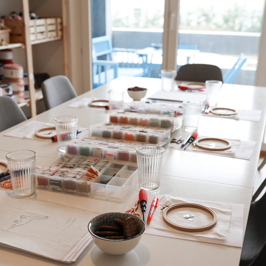 Atelier de broderie en petit groupe, avec tambours, fils et créations en cours sur la table